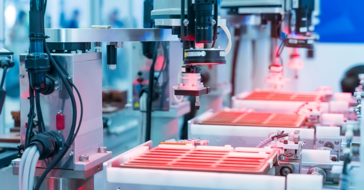 An industrial vision camera faces a circular test fixture as red lighting illuminates targets along a metal rail.