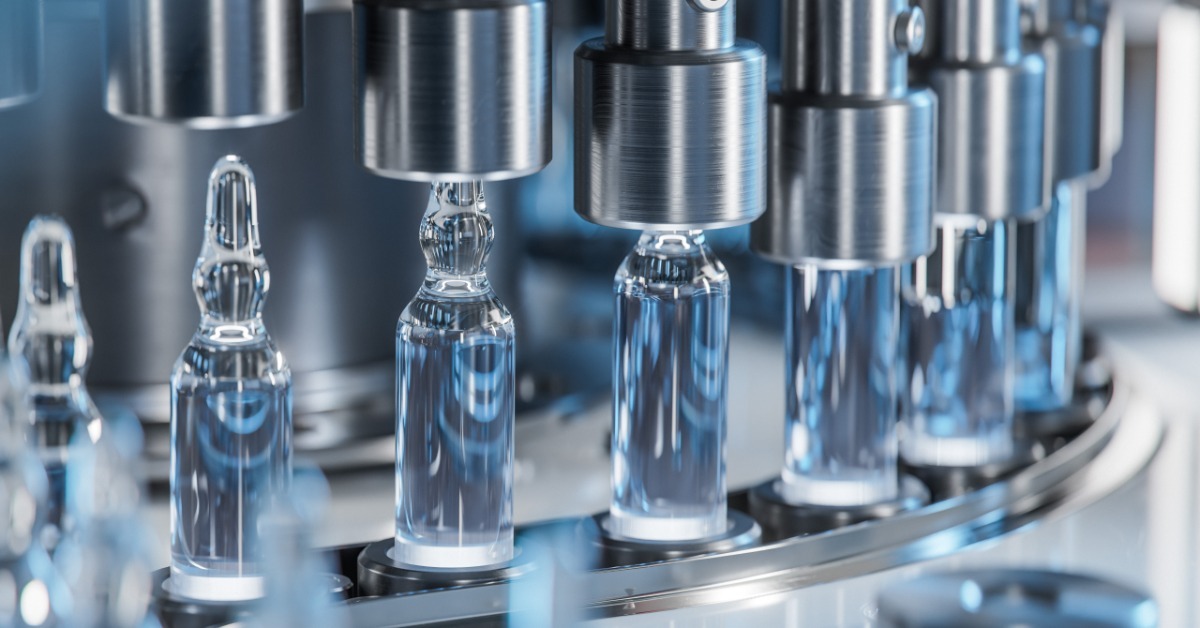 A filling machine processes clear glass ampoules as they move through a rotating pharmaceutical production line.