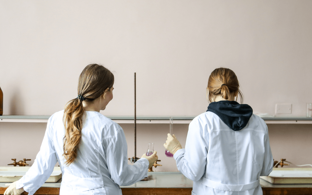 Image of two female scientists working with glass lab equipment for an article about 5 ways glass helped scientific discoveries.